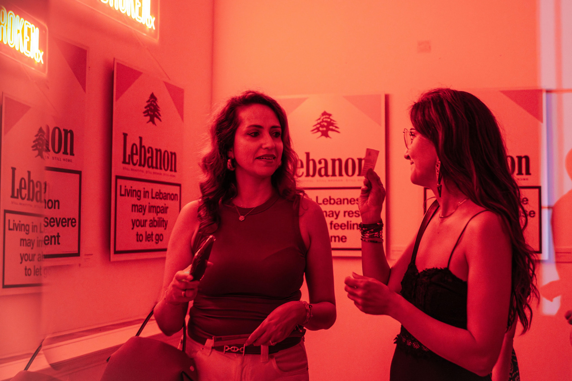 Two guests in conversation beneath the neon