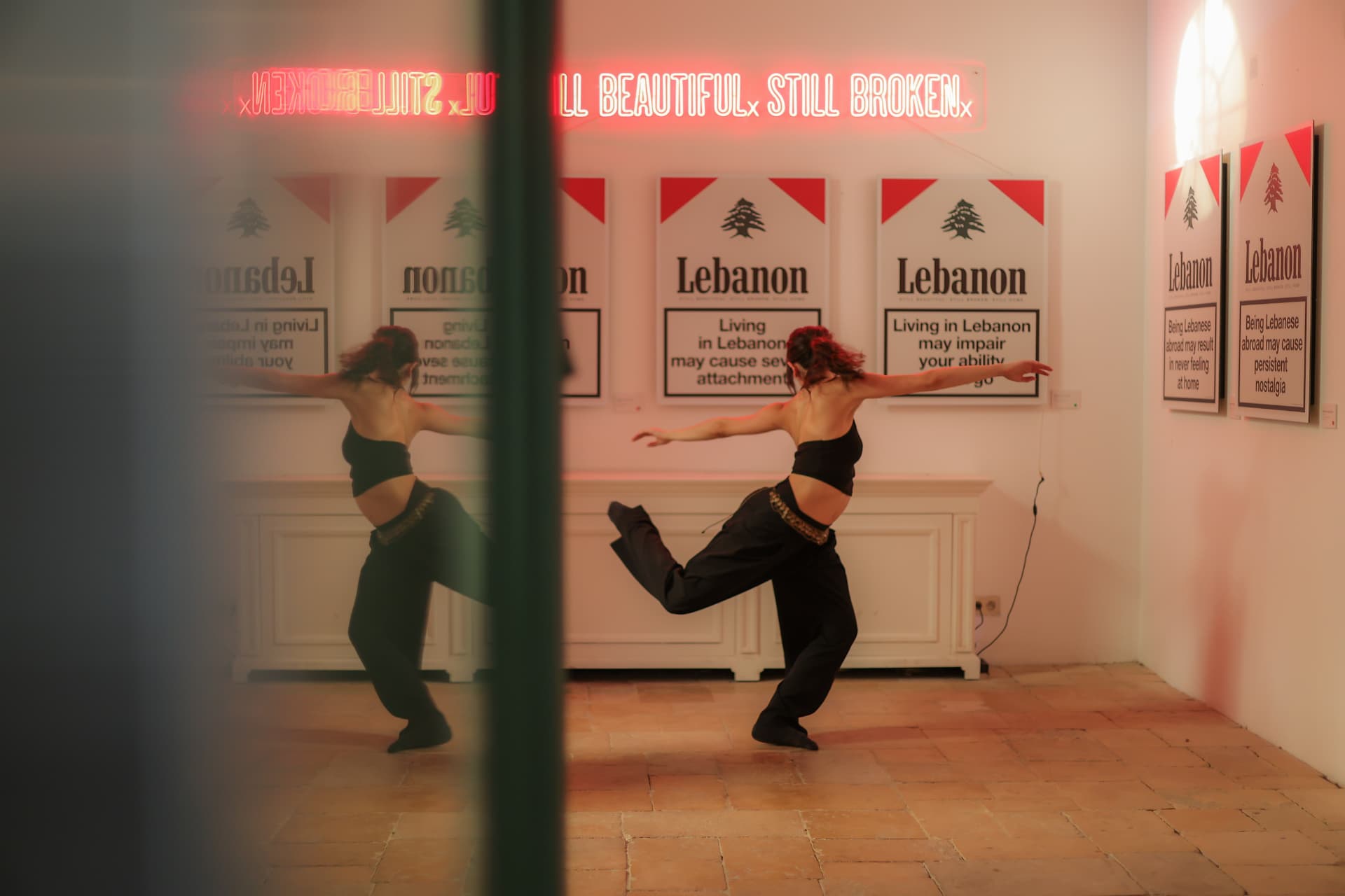 Dancer mid-movement before the wall of thirteen prints