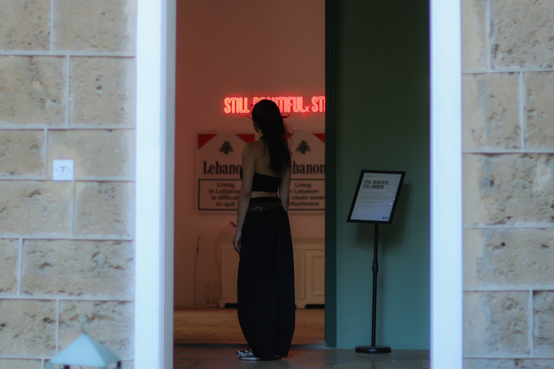 Visitor framed in the doorway before the neon and the prints